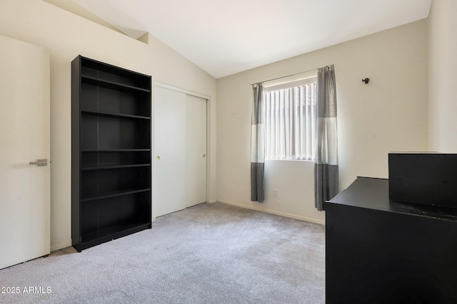 unfurnished bedroom featuring light colored carpet, vaulted ceiling, and a closet