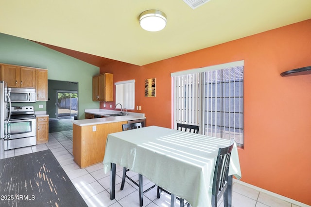 dining space with sink, light tile patterned floors, and vaulted ceiling