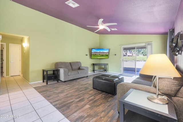 living room featuring tile patterned flooring, ceiling fan, a textured ceiling, and vaulted ceiling