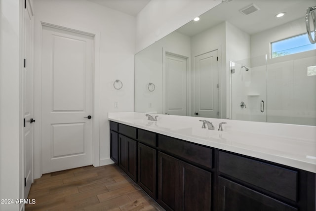 bathroom with a shower with door, hardwood / wood-style floors, and vanity