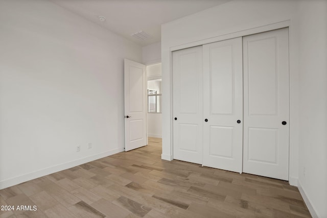 unfurnished bedroom featuring light wood-type flooring and a closet