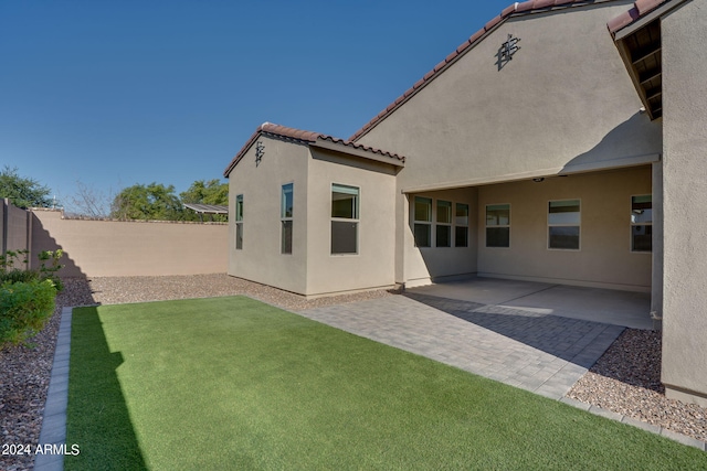 rear view of property featuring a patio and a lawn