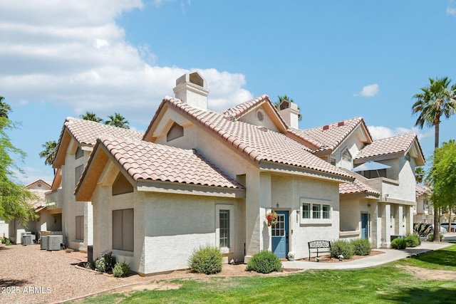 rear view of property with a lawn, central AC unit, stucco siding, and a chimney