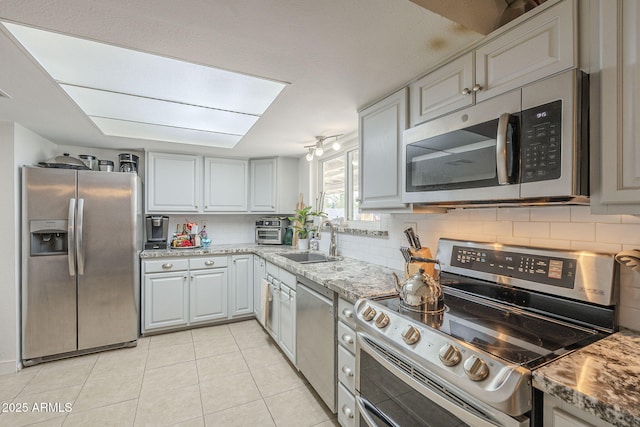 kitchen featuring light stone counters, sink, gray cabinets, and appliances with stainless steel finishes