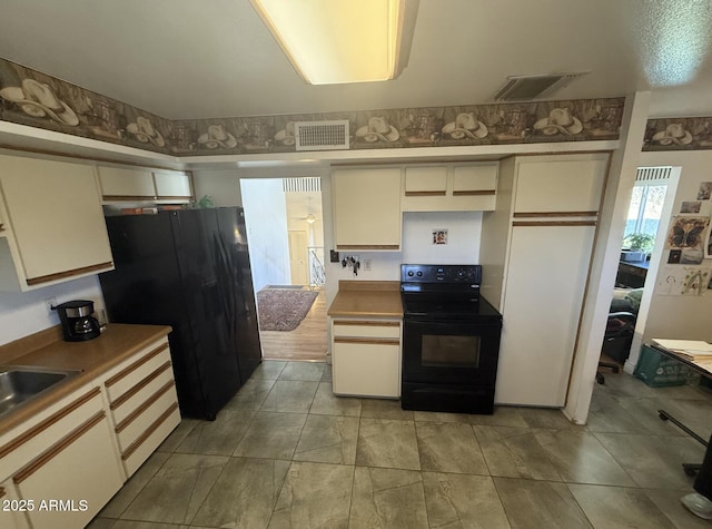 kitchen featuring black appliances, cream cabinets, light countertops, and visible vents