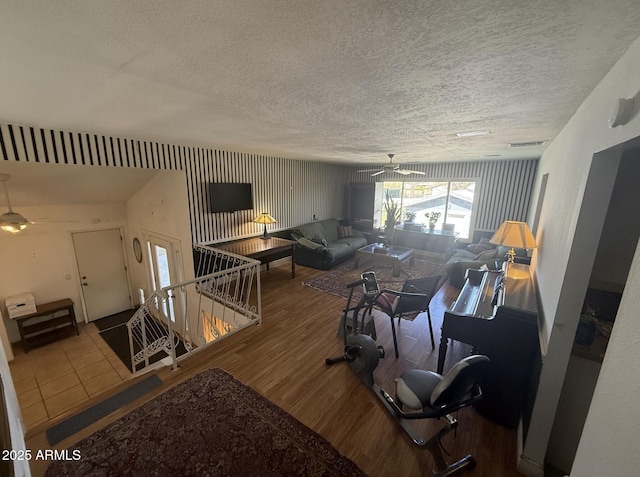 living room with a ceiling fan, a textured ceiling, visible vents, and wood finished floors