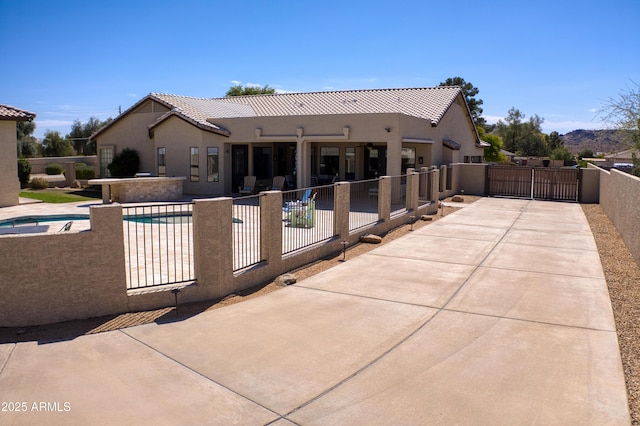 back of house with a gate, a patio area, and stucco siding