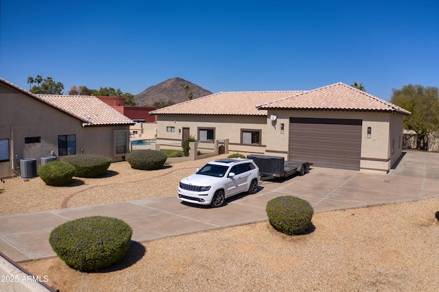 view of front of home with central AC unit, driveway, stucco siding, a garage, and a tiled roof