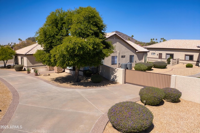 view of front of property featuring a tiled roof, a gate, fence, and stucco siding