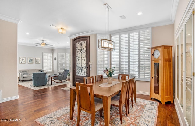 dining room with a wealth of natural light, baseboards, hardwood / wood-style floors, and crown molding