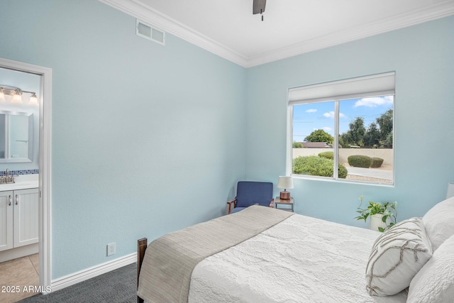 bedroom featuring visible vents, ensuite bathroom, a sink, crown molding, and baseboards