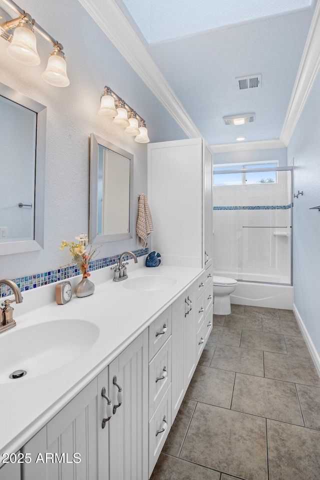 full bathroom featuring visible vents, crown molding, toilet, double vanity, and a sink