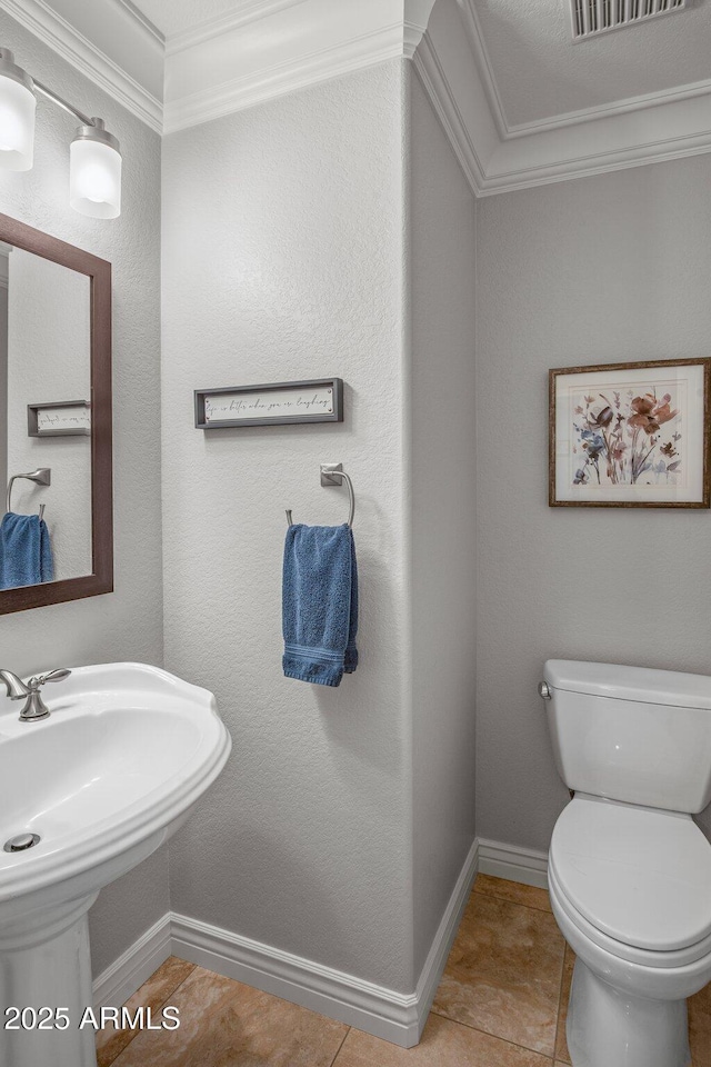 half bathroom featuring visible vents, baseboards, toilet, ornamental molding, and tile patterned floors