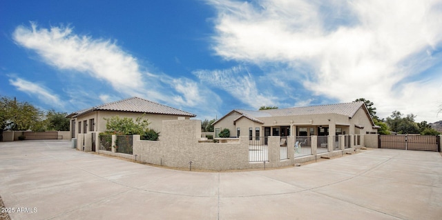 exterior space featuring a fenced front yard, stucco siding, a tile roof, and a gate