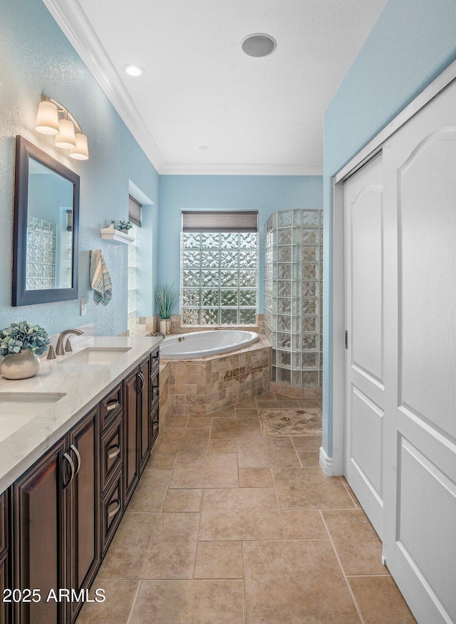 bathroom featuring double vanity, crown molding, a garden tub, and a sink