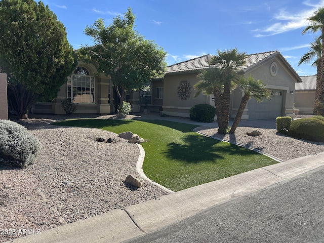 view of front of house with a front yard, a tiled roof, an attached garage, and stucco siding