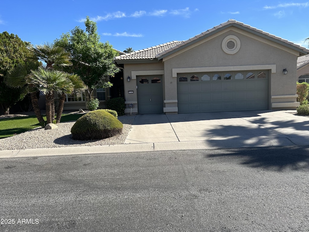 view of front of home with stucco siding, a garage, driveway, and a tiled roof