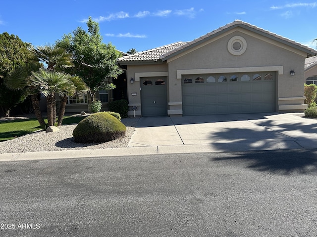 view of front of home with stucco siding, a garage, driveway, and a tiled roof