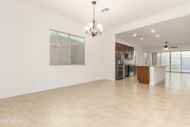 kitchen featuring light stone countertops, a kitchen island, decorative light fixtures, appliances with stainless steel finishes, and ceiling fan with notable chandelier