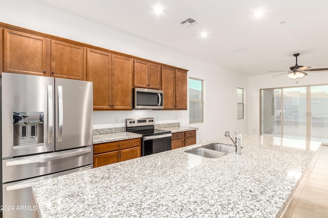 kitchen featuring appliances with stainless steel finishes, light stone counters, and sink