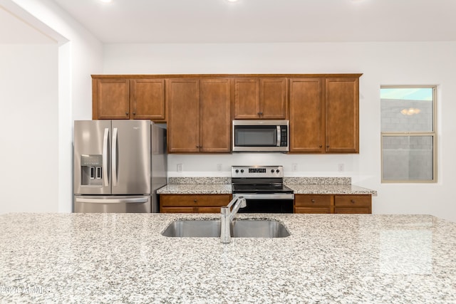 kitchen featuring light stone counters, appliances with stainless steel finishes, and sink