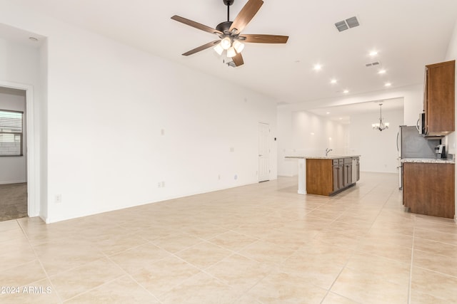 unfurnished living room with ceiling fan with notable chandelier and light tile patterned floors