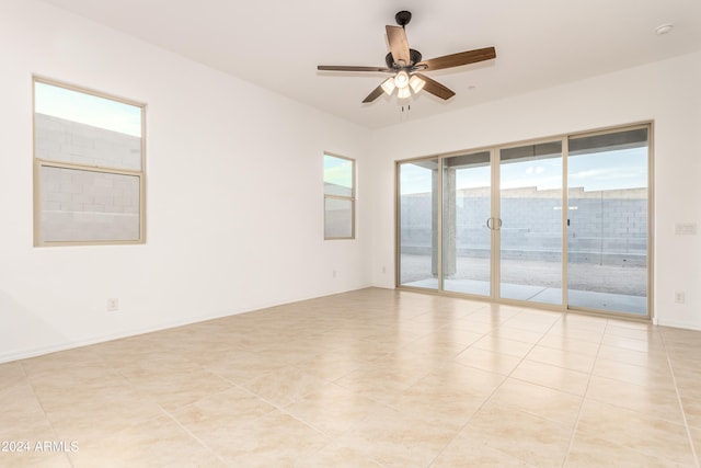 tiled empty room with ceiling fan and plenty of natural light