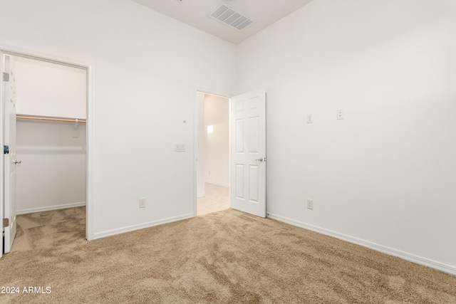 unfurnished bedroom with light colored carpet, a closet, and a walk in closet