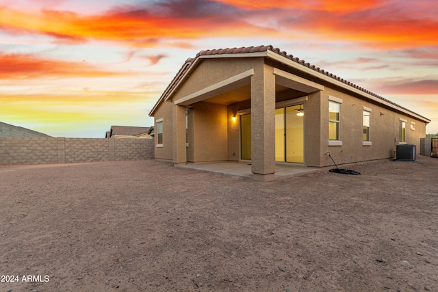 back house at dusk with central air condition unit and a patio area