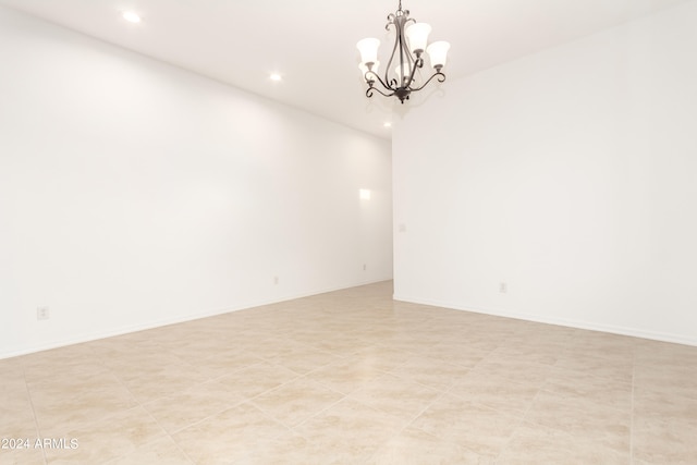 spare room with a chandelier and light tile patterned floors