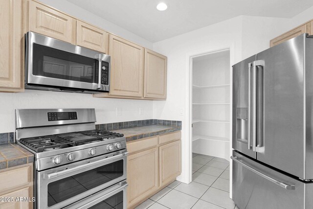 kitchen featuring light tile patterned flooring, appliances with stainless steel finishes, tile countertops, and light brown cabinets