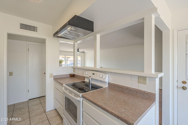 kitchen featuring visible vents, white electric stove, decorative backsplash, white cabinetry, and exhaust hood