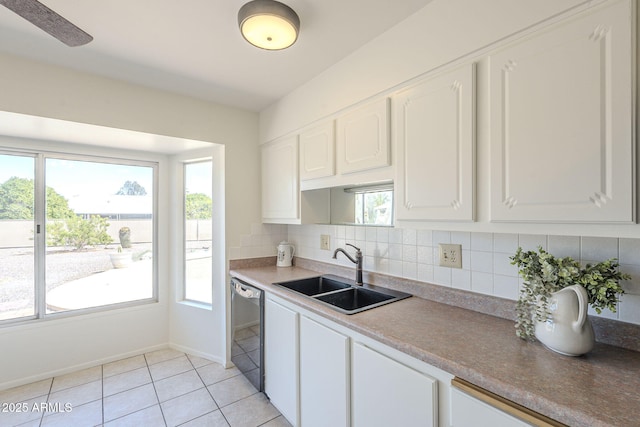 kitchen featuring tasteful backsplash, dishwashing machine, light tile patterned flooring, white cabinetry, and a sink