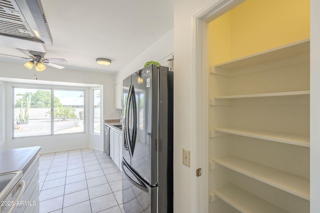 kitchen featuring built in shelves, light countertops, freestanding refrigerator, light tile patterned flooring, and white electric range