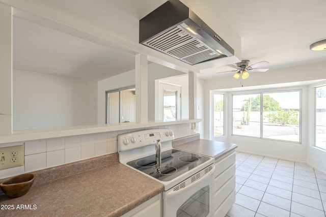 kitchen featuring light tile patterned floors, a ceiling fan, white electric stove, exhaust hood, and backsplash