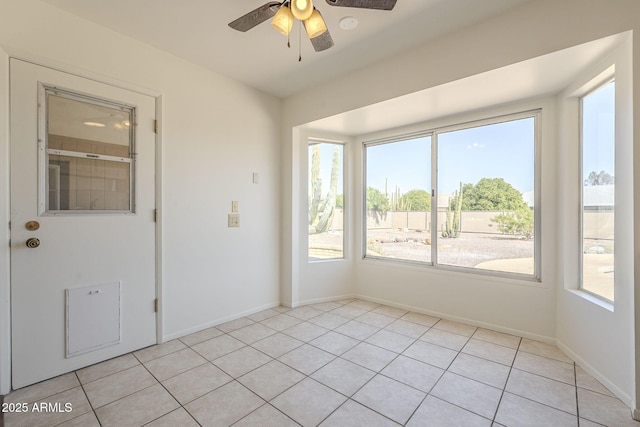 spare room featuring light tile patterned floors, a ceiling fan, and baseboards