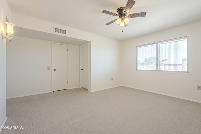 empty room with light carpet, visible vents, baseboards, and ceiling fan