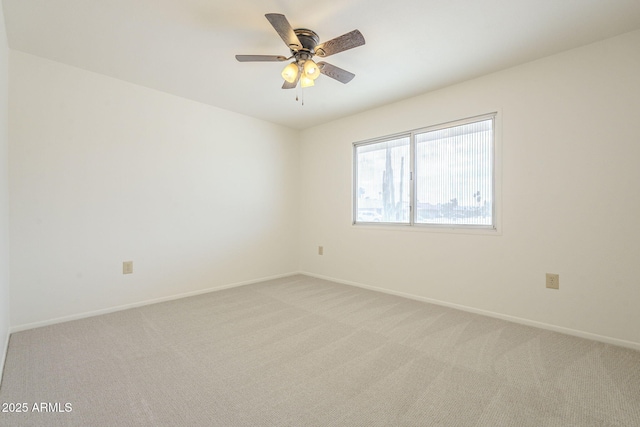 spare room featuring baseboards, light colored carpet, and a ceiling fan