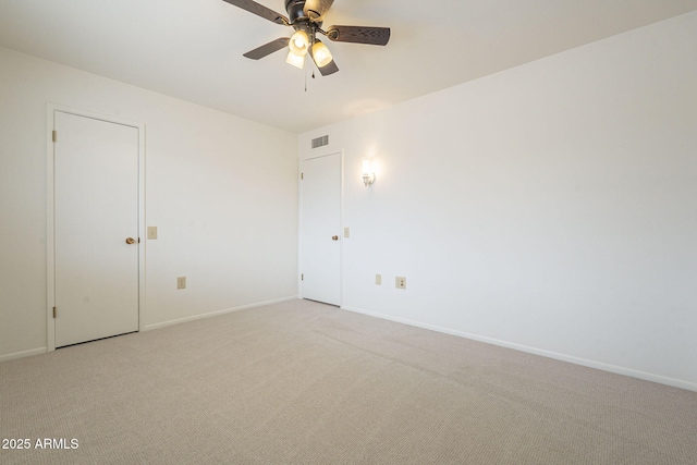 empty room with visible vents, light colored carpet, a ceiling fan, and baseboards