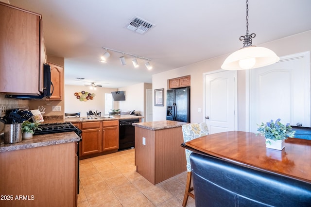 kitchen featuring light tile patterned floors, a sink, a kitchen island, visible vents, and black appliances