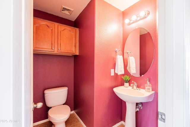 bathroom featuring toilet, baseboards, visible vents, and tile patterned floors