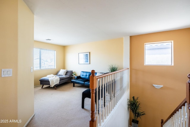 hall with carpet, visible vents, and an upstairs landing