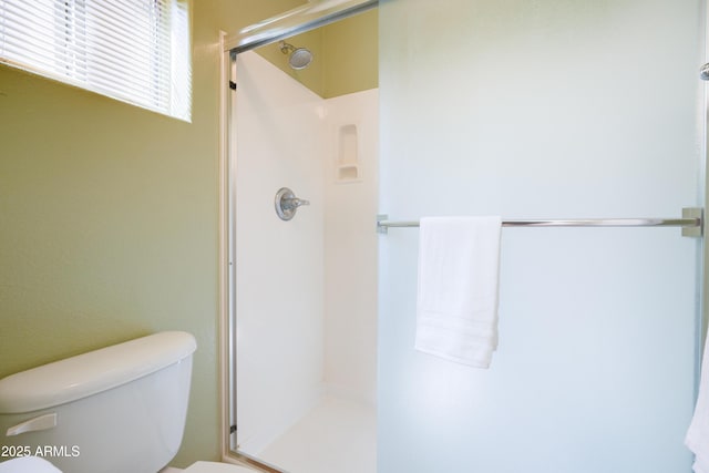 bathroom featuring toilet and a shower stall