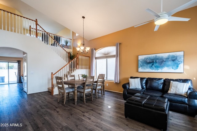 dining area with high vaulted ceiling, arched walkways, wood finished floors, and stairs