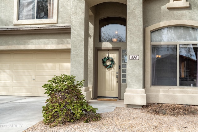 view of exterior entry featuring a garage and stucco siding