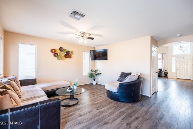 living area with arched walkways, visible vents, a ceiling fan, wood finished floors, and baseboards