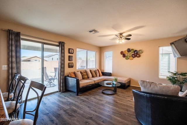 living area with dark wood-style flooring, plenty of natural light, and visible vents