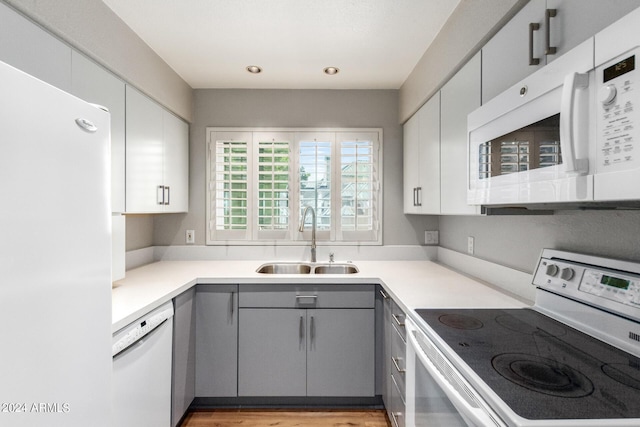 kitchen featuring gray cabinets, sink, and white appliances