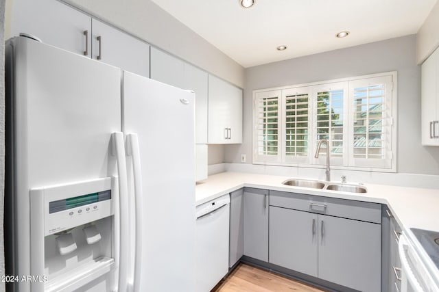 kitchen featuring gray cabinetry, light wood-type flooring, sink, and white appliances