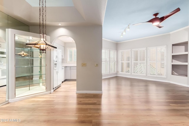 unfurnished dining area featuring light wood-type flooring, ceiling fan, and crown molding